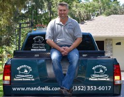Shane Mandrell, owner, on the tailgate of a Mandrell's company truck