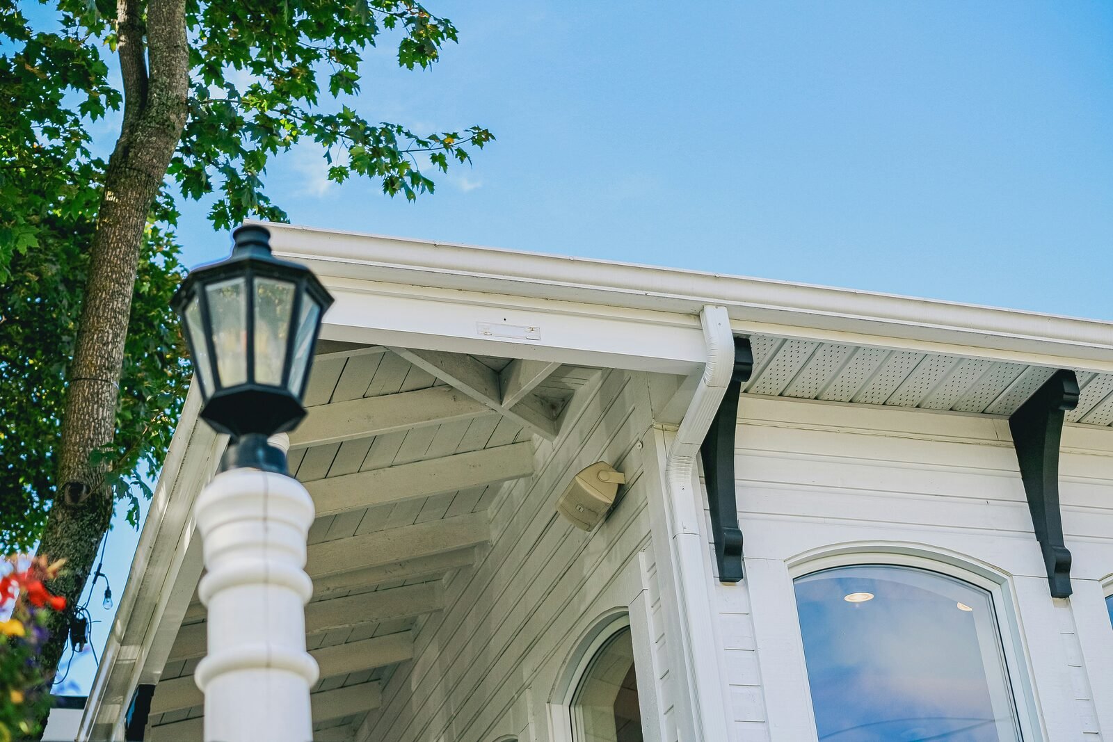 Gutter and soffit cleaning — white soffits and gutters under blue sky